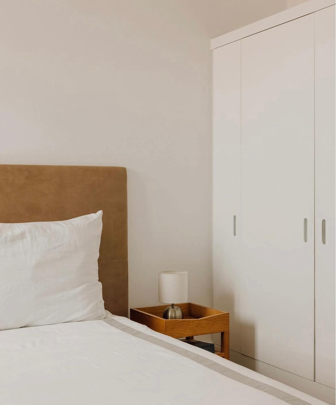 INDRA side table beside a bed in a room with light-coloured walls.