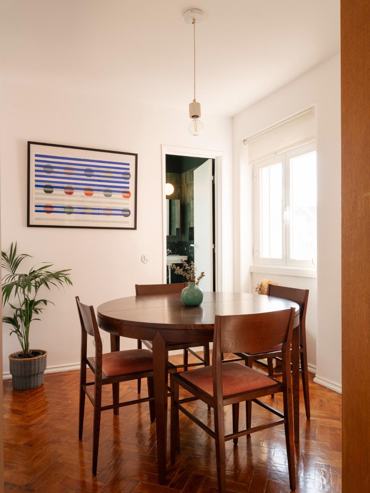Mesa de jantar redonda PERLA com cadeiras, num ambiente de sala de jantar.