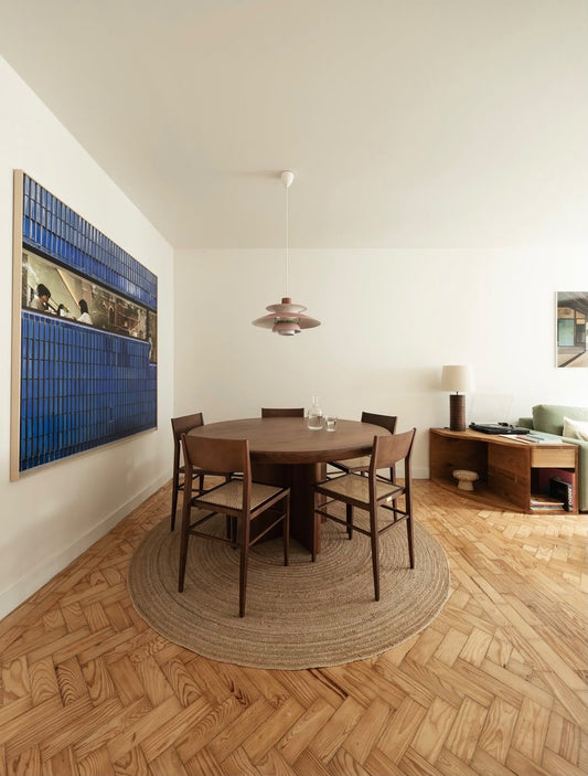 Mesa de jantar redonda RIA com cadeiras, num ambiente de sala de jantar.