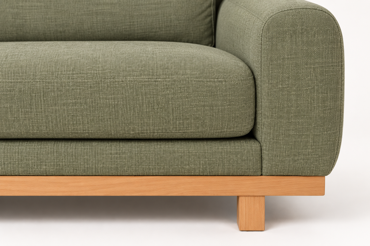 Detail of the rounded arm and wooden base of the green LIDO sofa.